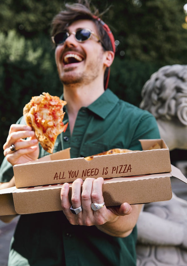 Uśmiechnięty Matteo Brunetti z kawałkiem pizzy i pudełkami